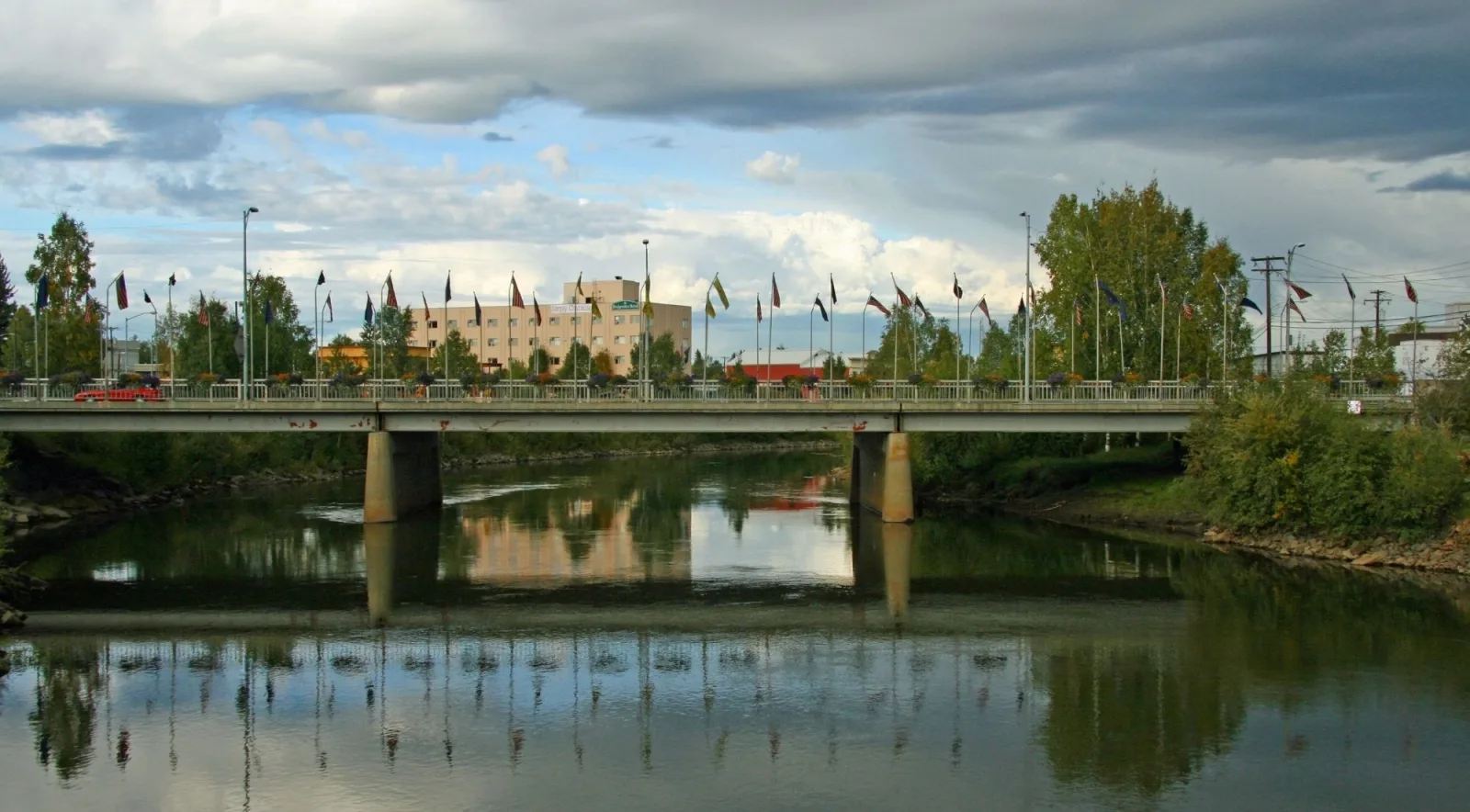 Bridge over the Chena River in downtown Fairbanks with flags along the railing in summer