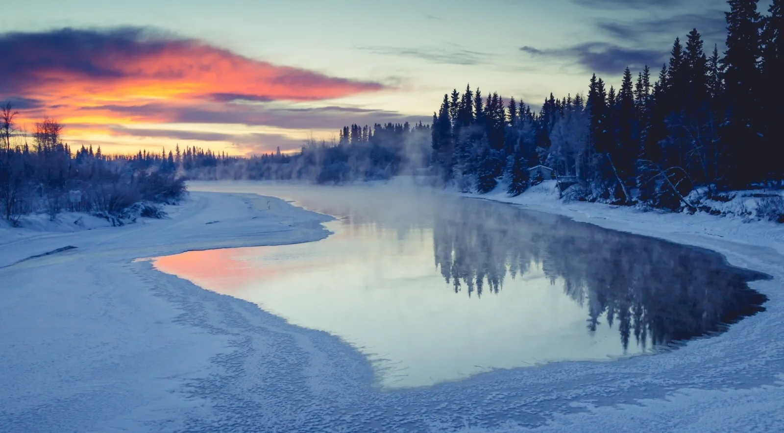 Pink sunrise over a steaming, partly frozen river lined with snowy spruce