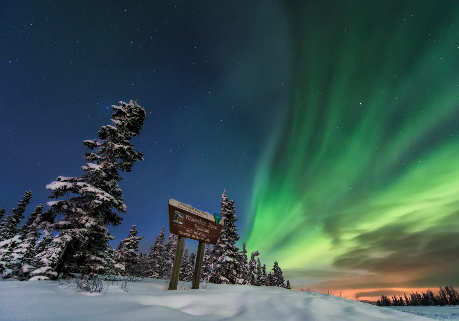 Green aurora above the Wickersham Dome Trailhead sign on the Elliott Highway, the road back toward Fairbanks