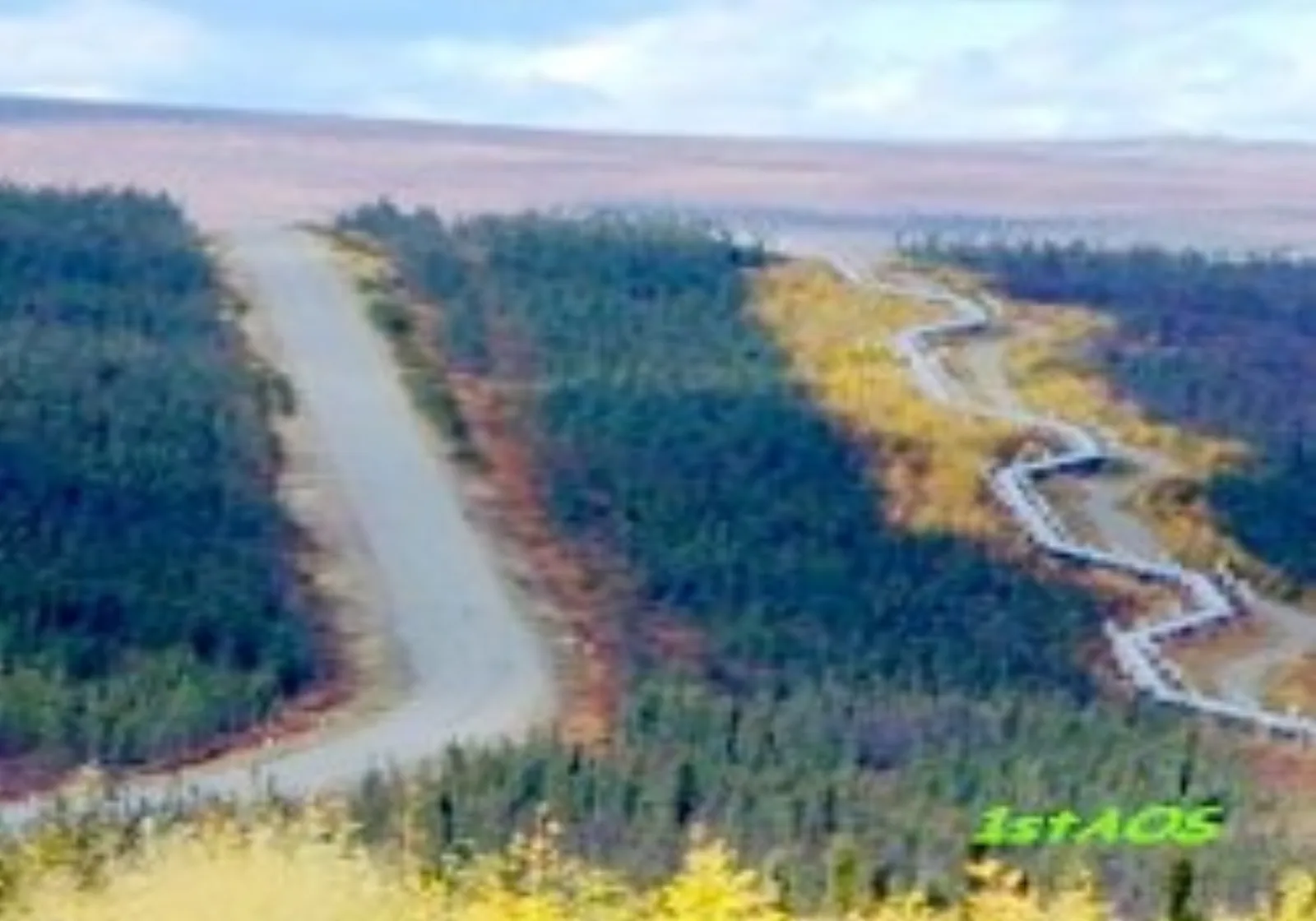Gravel Dalton Highway cutting through boreal forest beside the Trans-Alaska Pipeline, with open tundra beyond