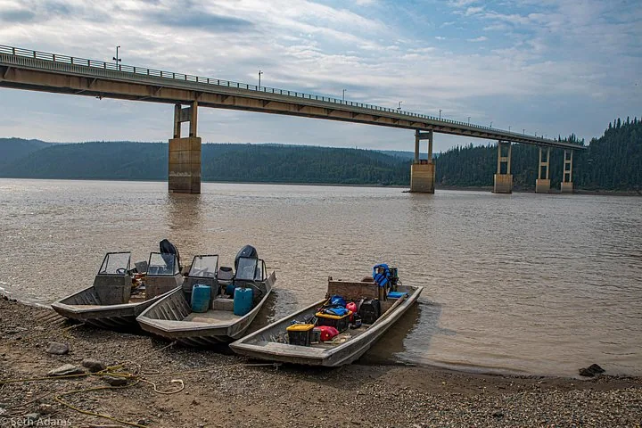 Yukon River bridge with riverboats pulled up on the gravel bank below