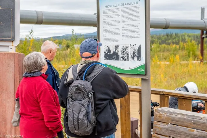 Tour guests reading the interpretive panel at the Trans-Alaska Pipeline viewing point