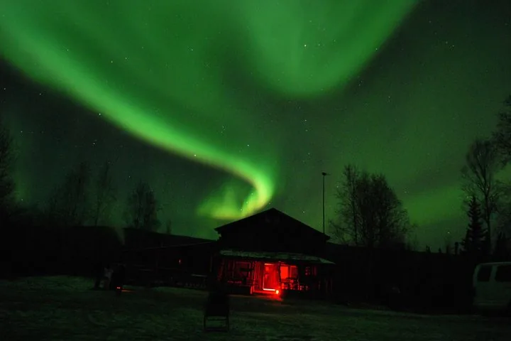 Aurora arc curving above the trading post at Joy with the tour van parked alongside