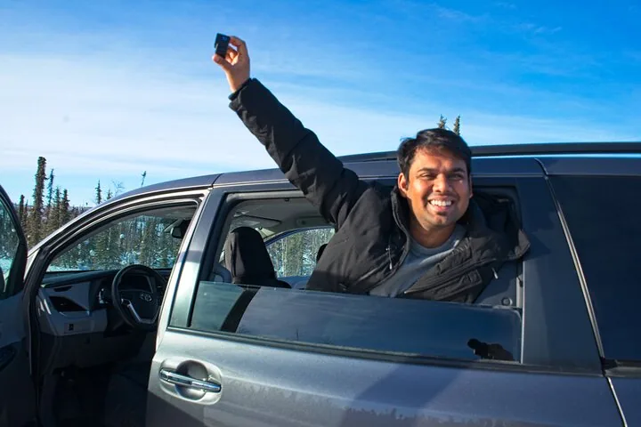 Guest leaning out of the window of the tour minivan under a blue winter sky