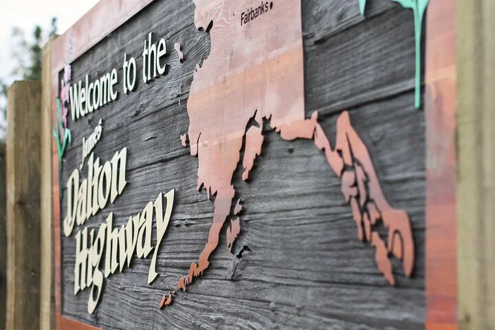 Close-up of the carved Welcome to the James Dalton Highway sign with its map of Alaska