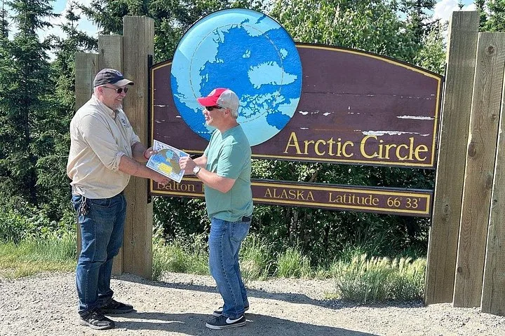 Guide presenting the personalized Arctic Circle certificate to a guest at the sign